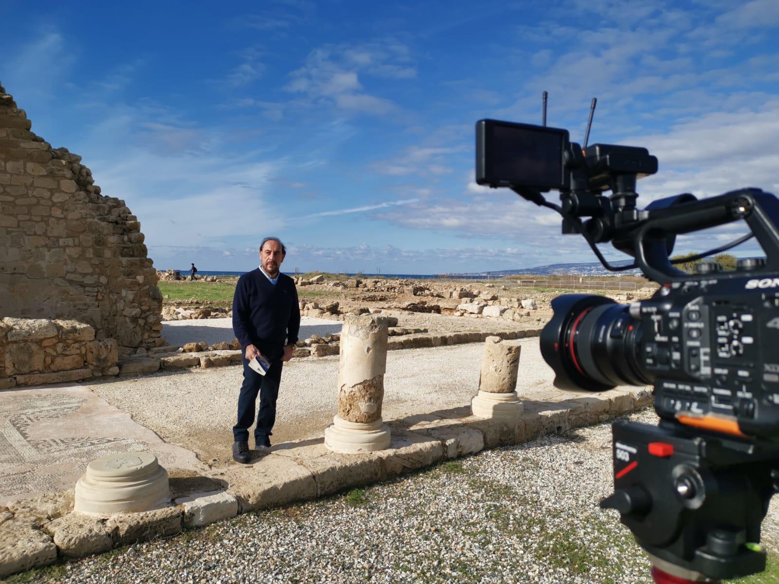 Pastor Chris on location at ancient Cypriot ruins, with the broadcast camera in the foreground