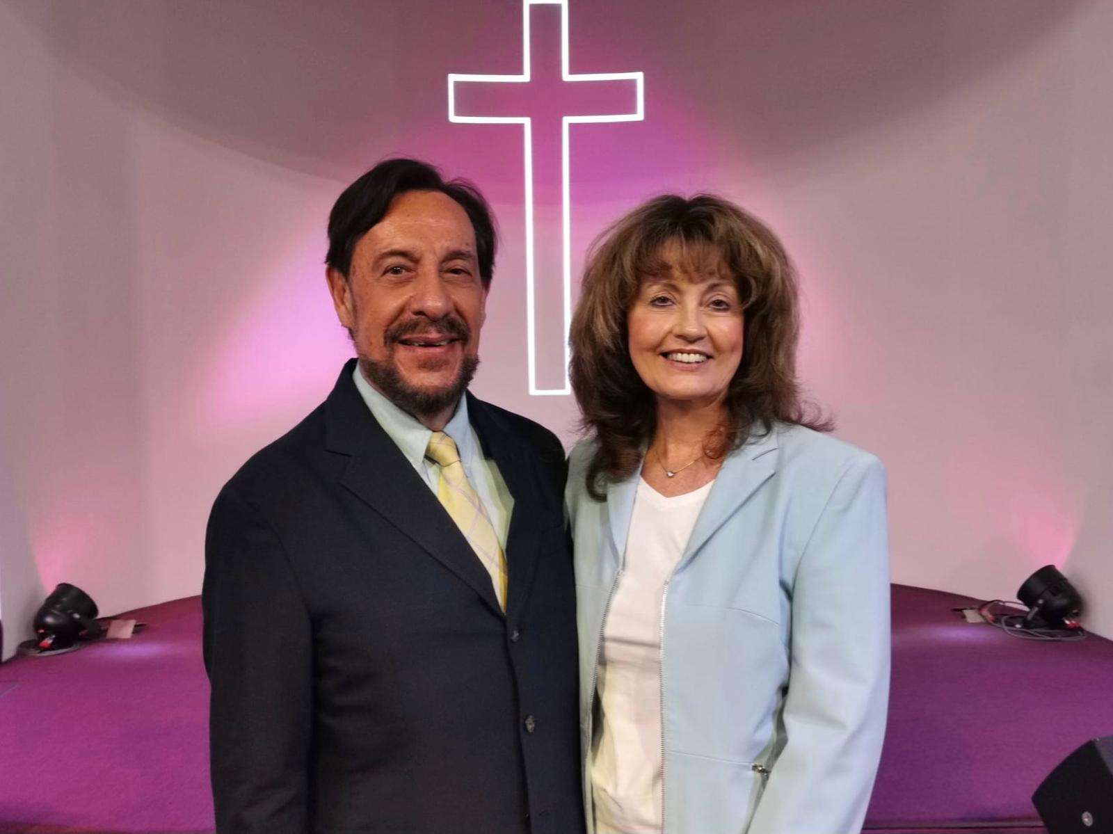 Pastors Chris and Loraine Demetriou together in front of the neon cross
