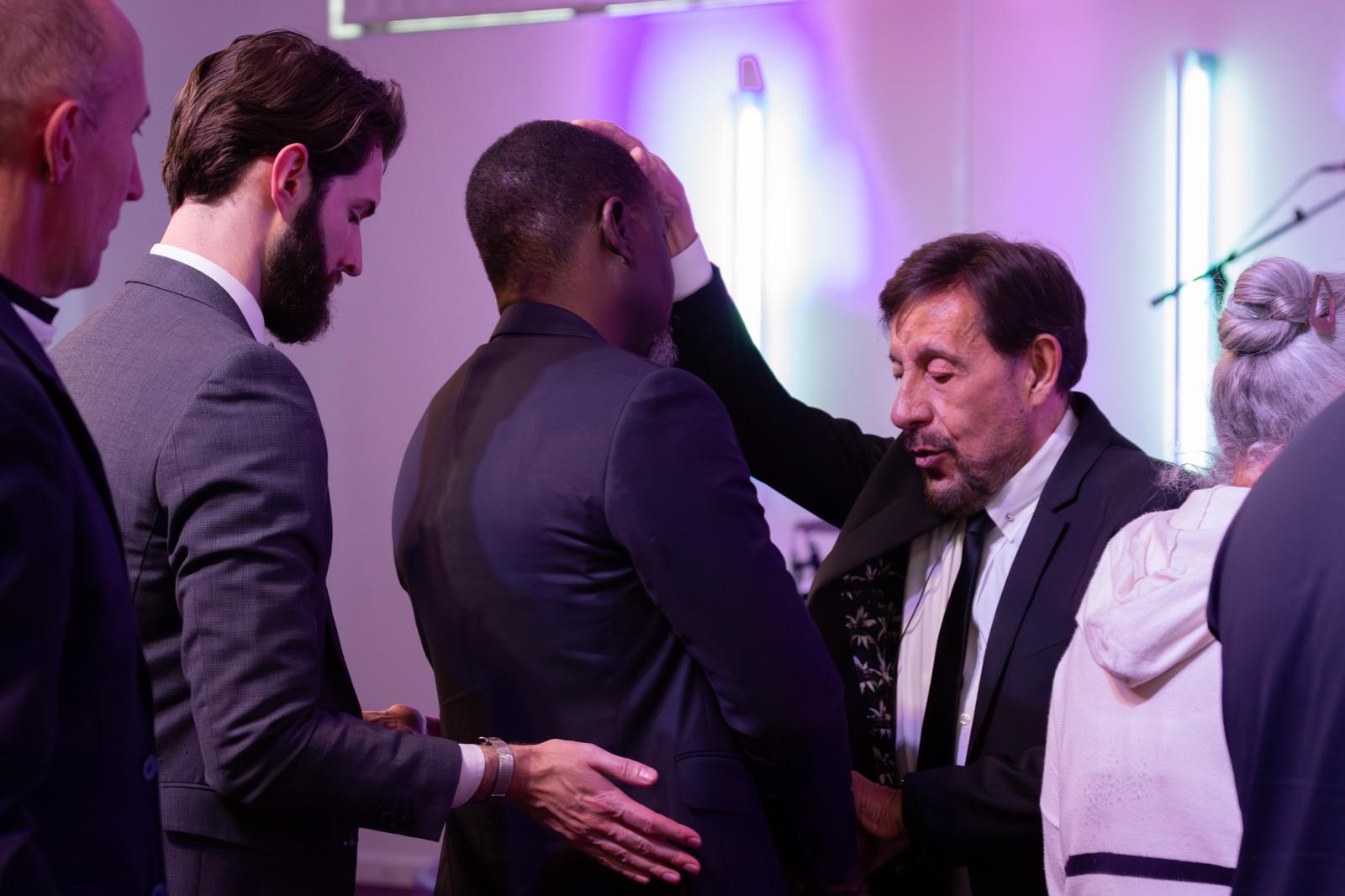 Pastor Chris laying hands in prayer alongside the ministry team