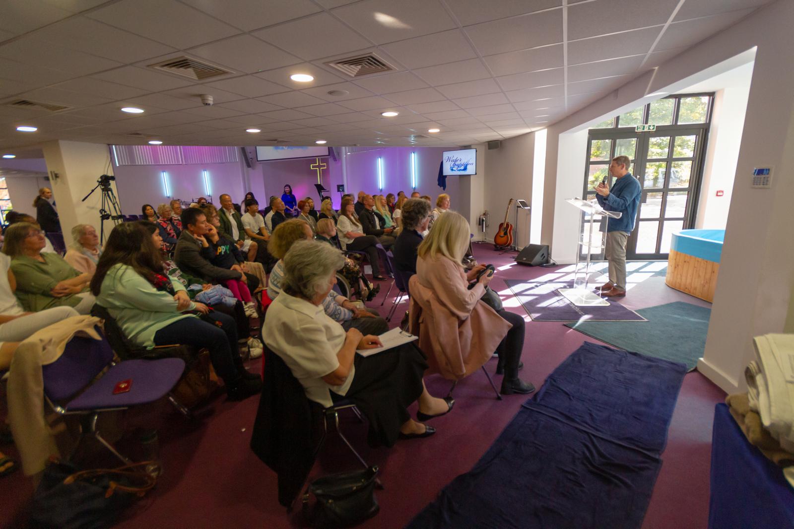 The congregation listening to the preacher, baptism pool visible at the front