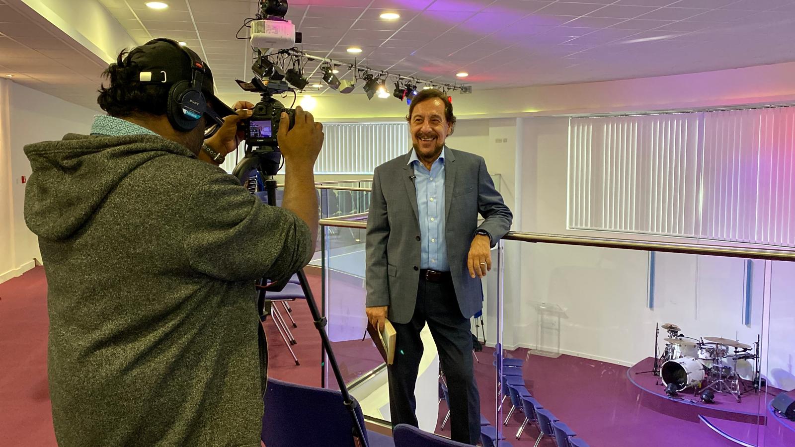 A Production team member filming Pastor Chris from the upper level