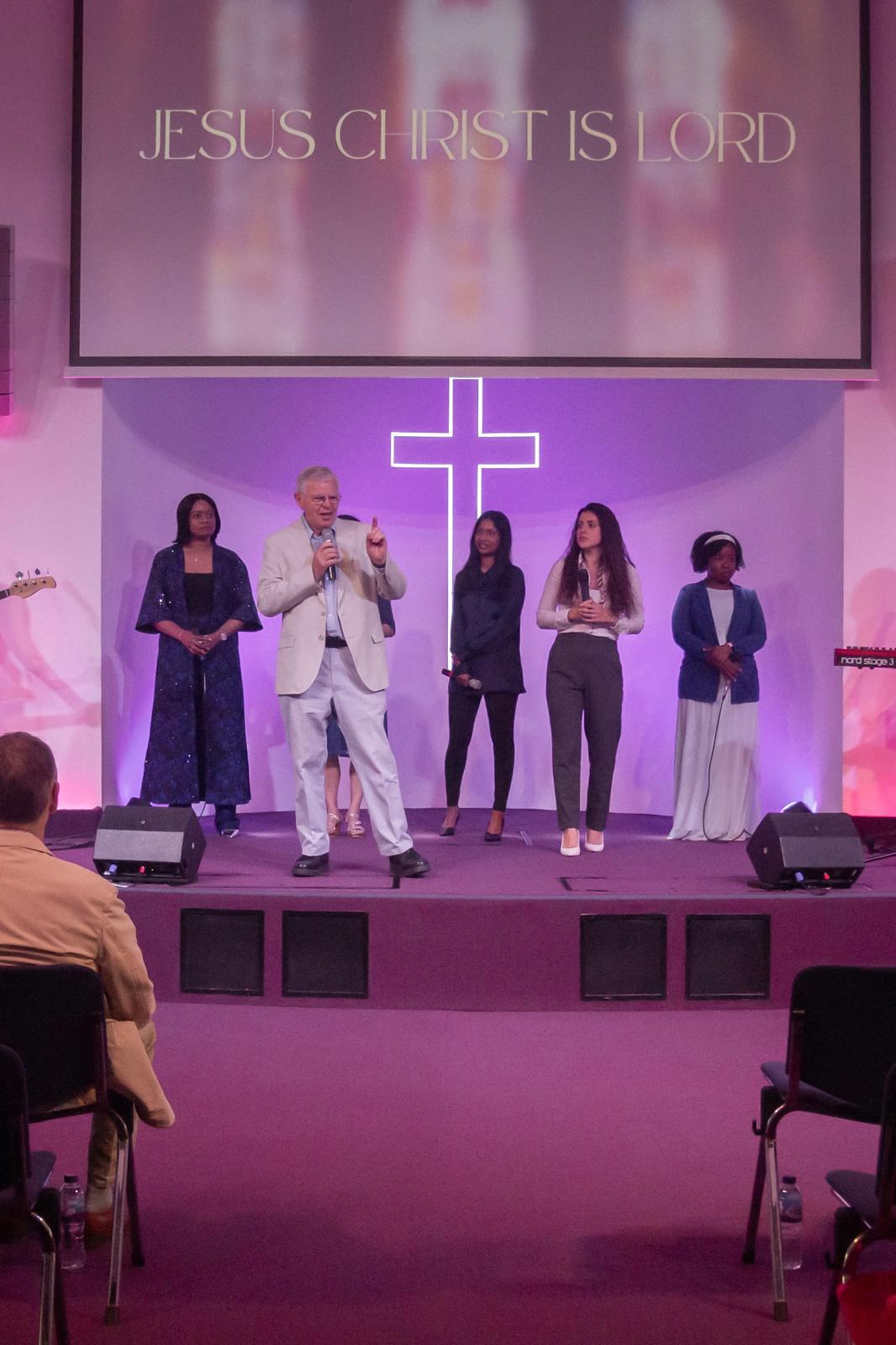 Opening in prayer on stage at Cornerstone, with the team beside him under the JESUS CHRIST IS LORD banner