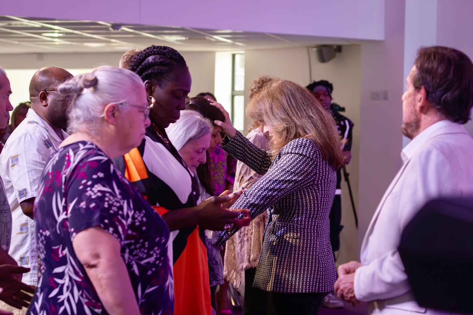 Pastor Loraine laying hands in prayer over a member of the congregation