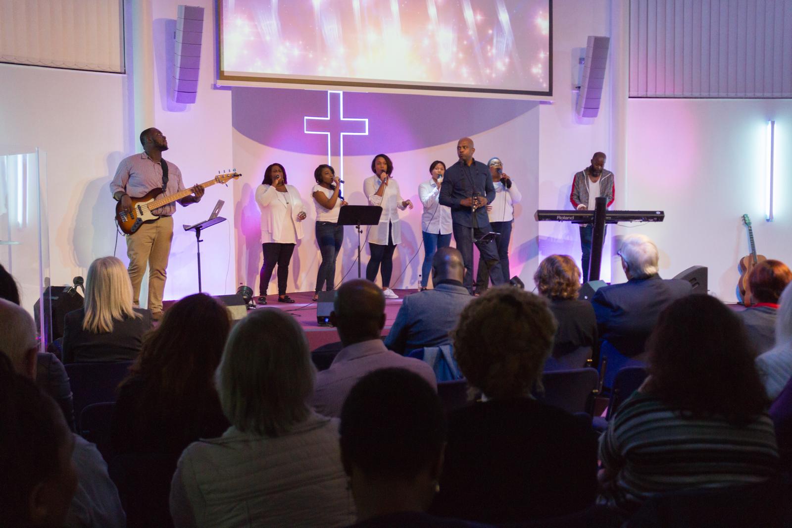 Brian Martin & Worship 4 Life leading the congregation in song under the neon cross