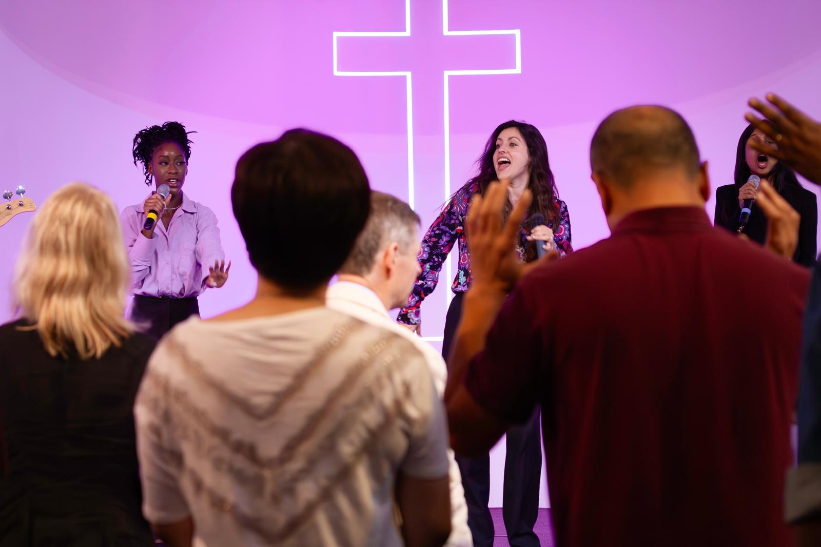 Two female vocalists on stage as the congregation lift their hands