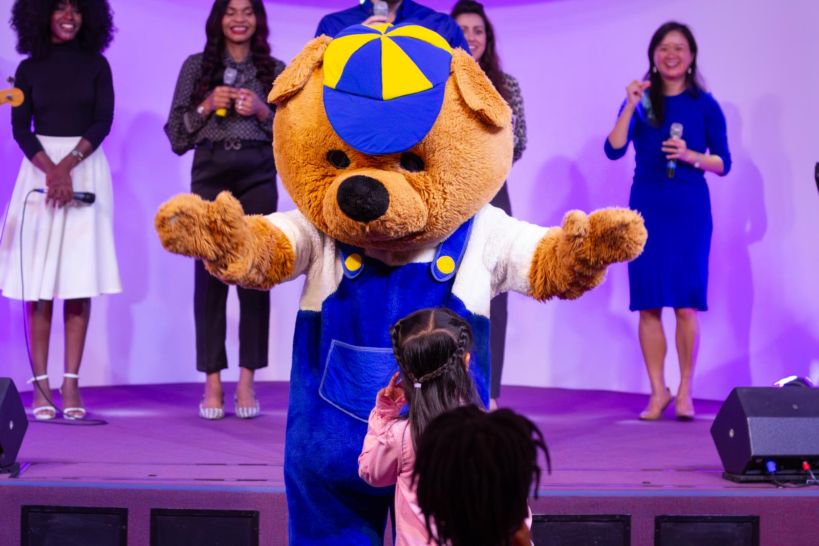 Godfrey the KidZone mascot dancing on stage with the worship band