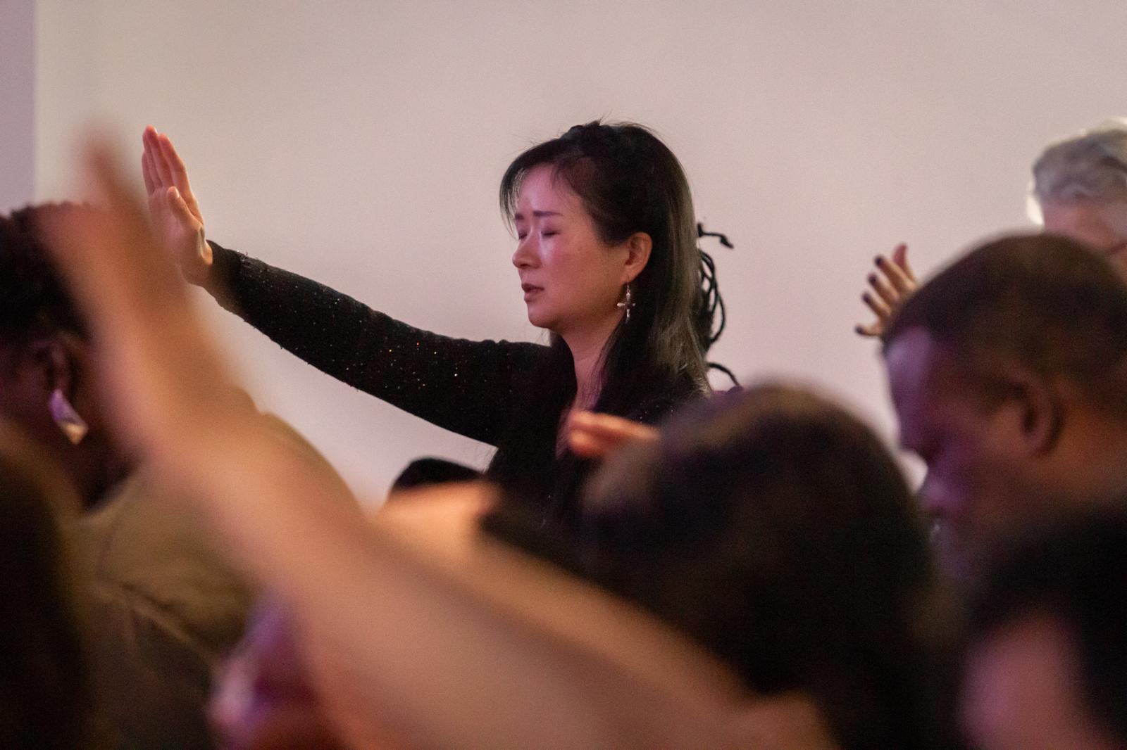 A woman raising her hand in worship, eyes closed